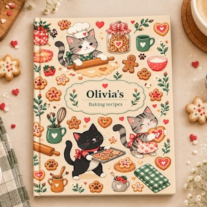 May include: A hardback book titled Olivia's Baking recipes with a cream-coloured cover featuring illustrations of three cats baking, heart-shaped biscuits, rolling pins, jars, and floral patterns in shades of red, green, and brown.