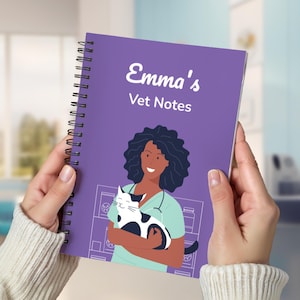 May include: A purple spiral-bound notebook with the text "Emma's Vet Notes" in white. The cover features an illustration of a veterinarian holding a black and white cat. The notebook is held in two hands.