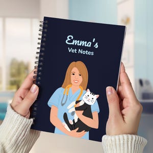 May include: A spiral-bound notebook with a navy blue cover featuring the text "Emma's Vet Notes." The cover illustration depicts a veterinarian in scrubs holding a black and white cat. The notebook is held by a person wearing a white sweater.