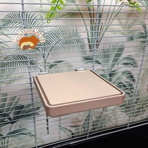 May include: A beige, rectangular bird perch with rounded edges, attached to a cage with two silver clips. The perch is made of a smooth, durable material and is designed to be easy to clean.
