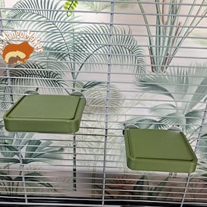 May include: Two green plastic platforms for small animals, such as hamsters or gerbils, are attached to the inside of a wire cage. The platforms are designed to provide additional space for the animals to play and explore.