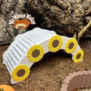 May include: A white, arched pet habitat bridge with yellow sunflower accents and brown centres. The bridge has a ribbed design and is decorated with the text "Mr Mango Makes".