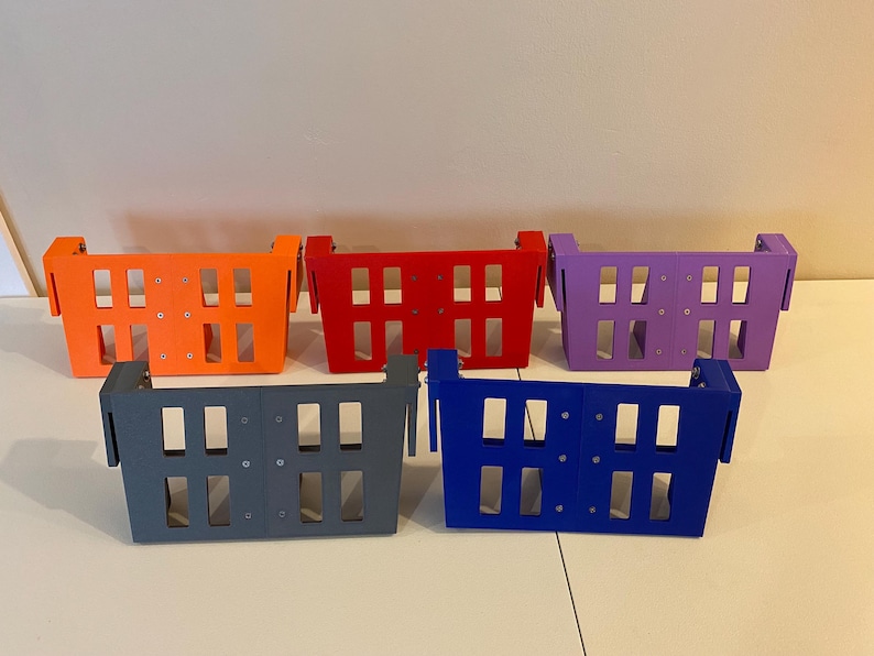 May include: Five colorful, rectangular storage baskets in orange, red, purple, gray, and blue. Each basket has a series of rectangular cutouts and a handle on each side. The baskets are arranged on a white surface.