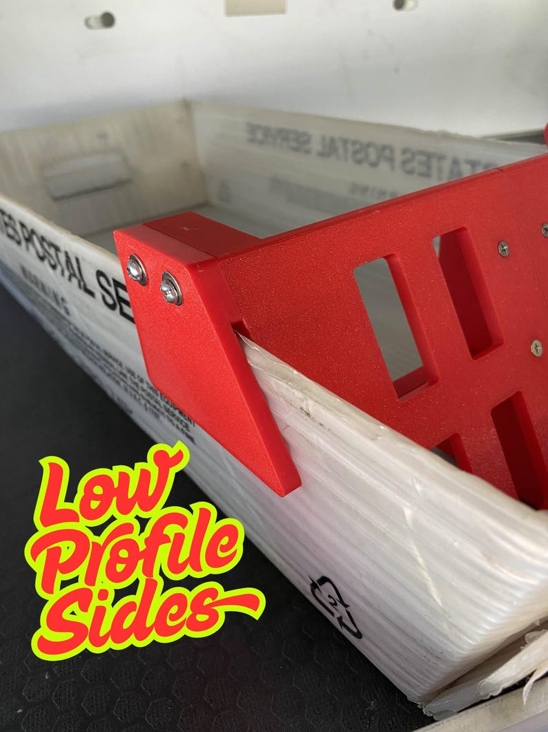 May include: A red plastic bracket with a rectangular design is attached to a white box. The box has text that reads "UNITED STATES POSTAL SERVICE". The image also contains the text "Low Profile Sides" in a yellow and red font.