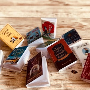May include: A collection of miniature books with various titles, including "Winnie the Pooh", "Peter Pan", "Charlie and the Chocolate Factory", "The Tale of Peter Rabbit", and "Grimm's Fairy Tales".