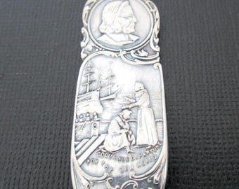 May include: Silver spoon with an embossed design. The spoon features a portrait, a ship, and figures in a scene. The text on the spoon reads "COLUMBUS DEPARTURE FOR THE NEW WORLD" and "1893".