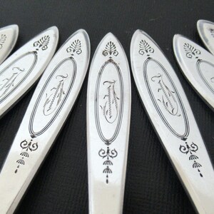 May include: Close-up of a set of silver flatware with an ornate design. The flatware has a decorative pattern of leaves and swirls.