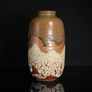 May include: A handcrafted ceramic vase with a unique, textured design. The vase features a blend of earthy tones, including brown, beige, and hints of green. The lower portion has a textured, almost coral-like appearance, adding visual interest.