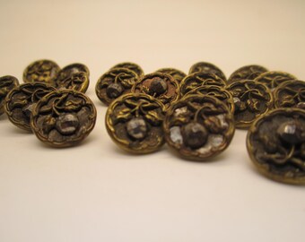 May include: A collection of antique brass buttons with a floral design. Each button features a central jewel and intricate detailing. The buttons have a vintage aesthetic, with a tarnished, aged appearance. Ideal for sewing and craft projects.