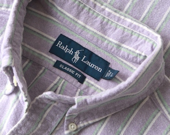 Könnte beinhalten: Ein langärmeliges Hemd mit Knopfleiste und einem vertikalen Streifenmuster in Lavendel, Weiß und Hellgrün. Der Kragen enthält ein dunkelblaues Etikett mit dem Text Ralph Lauren, ein kleineres Etikett Classic Fit und ein L-Größenschild.