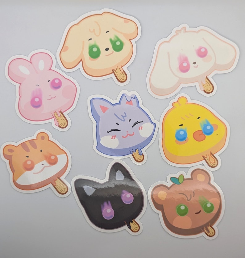 May include: A collection of eight cartoon animal-shaped stickers resembling popsicles. The stickers feature a variety of animals, including a dog, bunny, cat, chick, tiger, and bear, in pastel colors with cute expressions.
