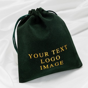 May include: A dark green velvet drawstring bag with gold text that reads "YOUR TEXT LOGO IMAGE". The bag has a matching green drawstring closure. The bag is likely used for packaging or storage.