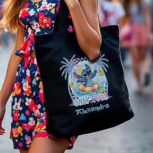 May include: A woman wearing a floral dress and Minnie Mouse ears, carrying a black tote bag. The tote bag features a Stitch graphic with the text "ONLY POOL" and a name. The background shows a theme park with blurred figures.
