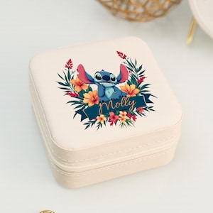 May include: A cream-colored square jewelry box with a zipper closure. The top features a colorful illustration of a blue cartoon character surrounded by flowers and greenery, with the name "Molly" in gold script.