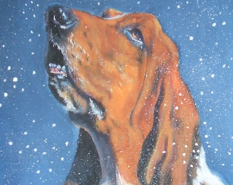May include: An oil painting depicting a Basset Hound looking upwards with its mouth open, as if catching snowflakes. The dog has brown and white fur against a dark blue background with white flakes. The artist's signature, L.A. SHEPARD ART, is visible.