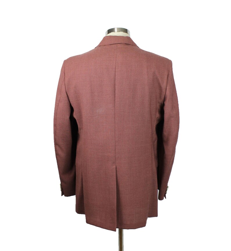 May include: A dusty rose blazer with a single button closure and long sleeves. The blazer is made of a textured fabric and has a classic fit.