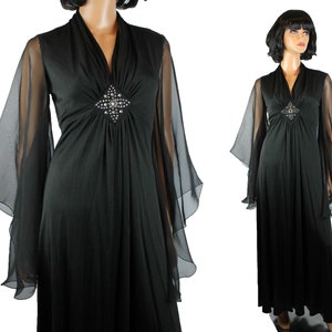 May include: A black maxi dress with long sheer sleeves and a jeweled embellishment at the neckline.