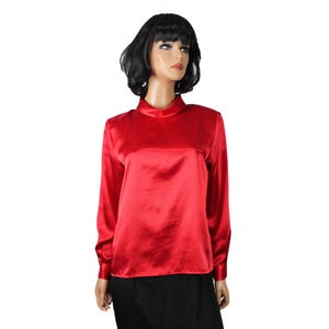 Op de afbeelding: Een rode satijnen blouse met een hoge hals en lange mouwen.