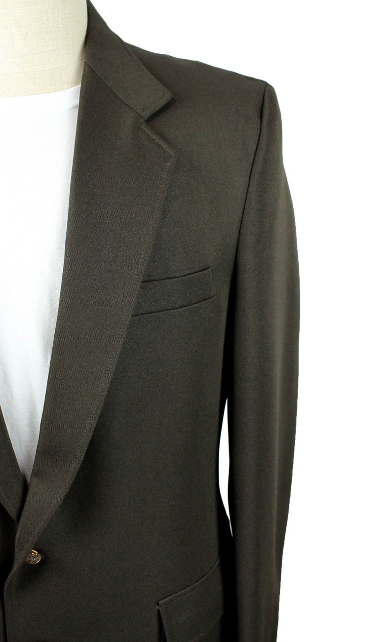Op de afbeelding: Een donkerbruin blazer met een enkele knoopsluiting en een klepzak aan de linkerkant.
