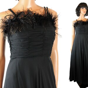 May include: A black floor-length gown with a feather trim around the neckline. The dress has a fitted bodice and a flowing skirt.