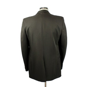 Op de afbeelding: Een donkergroen blazer met een enkele knoopsluiting. De blazer is gemaakt van een gladde, gestructureerde stof.