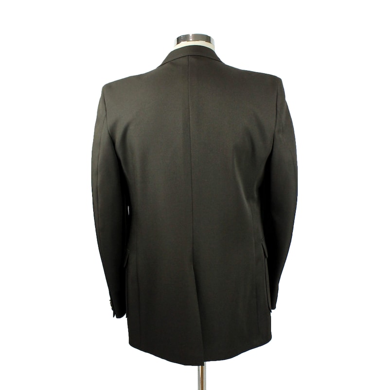 Op de afbeelding: Een donkergroen blazer met een enkele knoopsluiting. De blazer is gemaakt van een gladde, gestructureerde stof.