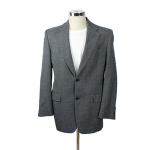 Puede incluir: Una chaqueta de traje gris a cuadros con cierre de dos botones y bolsillos de solapa.