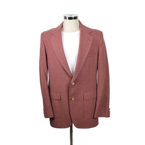 May include: A maroon blazer with a single button closure and two front pockets. The blazer has a classic style and is made of a soft, textured fabric.