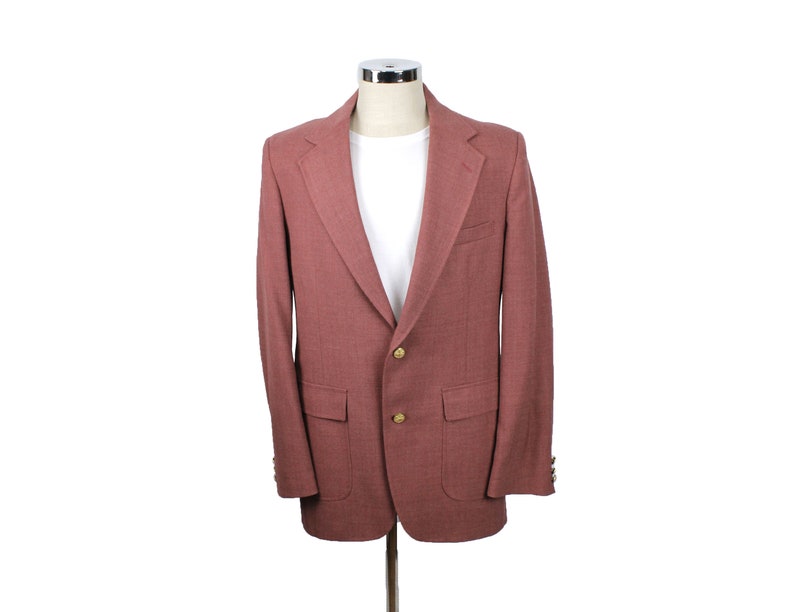 May include: A maroon blazer with a single button closure and two front pockets. The blazer has a classic style and is made of a soft, textured fabric.
