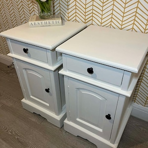 A pair of slim, solid pine bedside cabinets, finished in a soft neutral paint