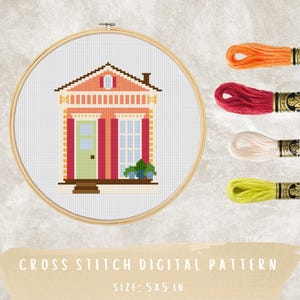 May include: A cross-stitch digital pattern of a house in a wooden embroidery hoop. The house features a peach-colored facade, a green door, and a blue window. The image includes spools of orange, red, cream, and yellow embroidery floss. The pattern size is 5x5 inches.