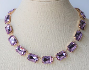 May include: A delicate gold chain necklace with a row of large, rectangular, light purple crystals.