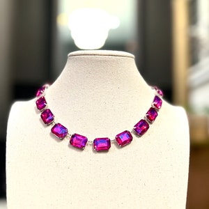 May include: A silver chain necklace with a row of large, rectangular, iridescent pink gemstones.