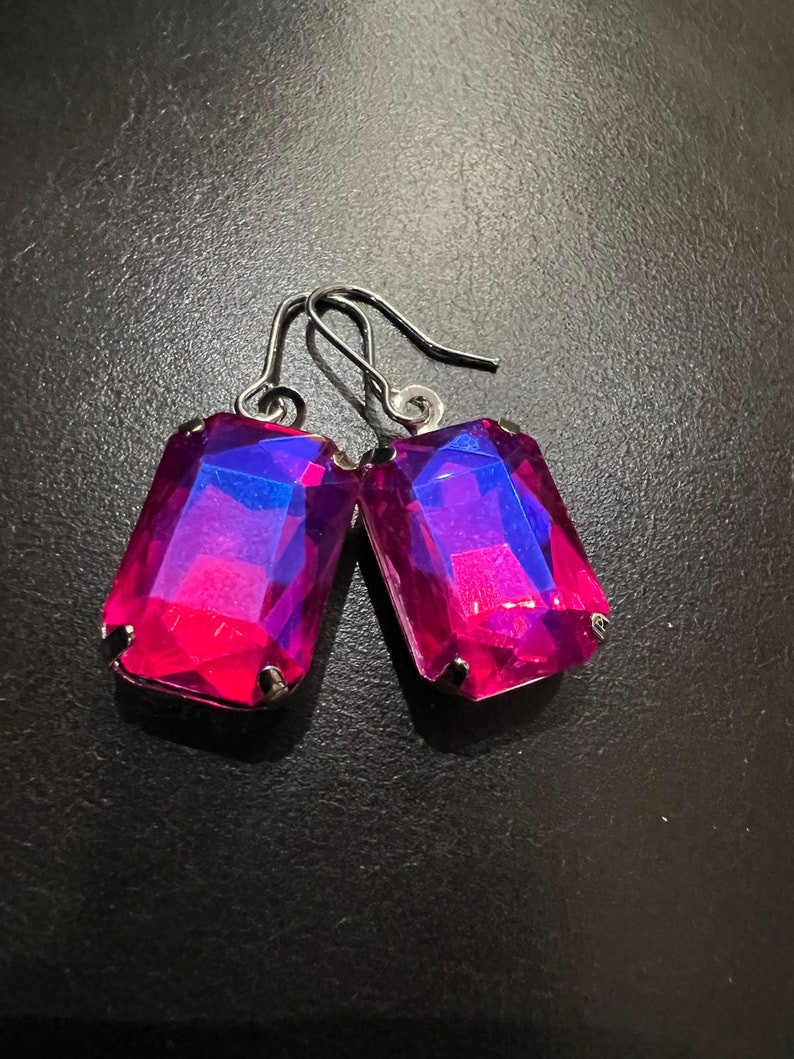 May include: A pair of silver dangle earrings with large, rectangular, iridescent pink and blue gemstones.