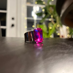 May include: A silver ring with a large, rectangular, pink and blue gemstone.