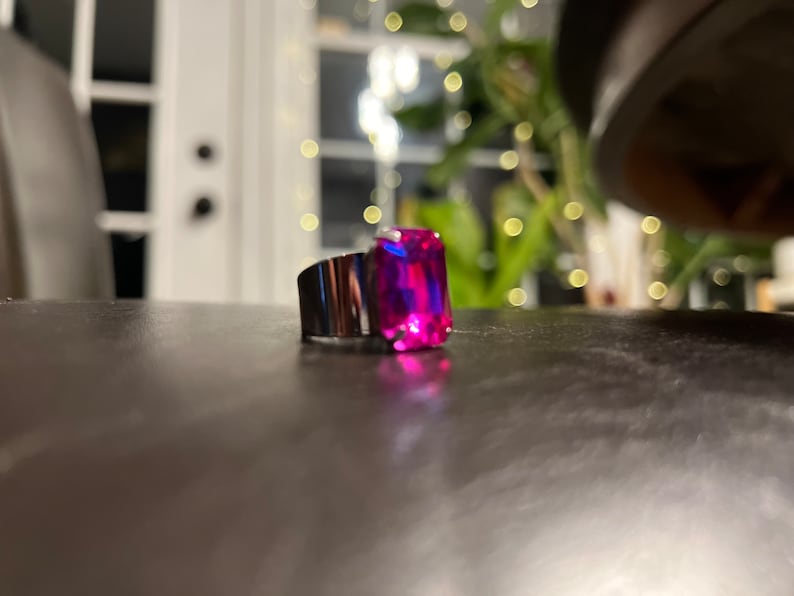 May include: A silver ring with a large, rectangular, pink and blue gemstone.