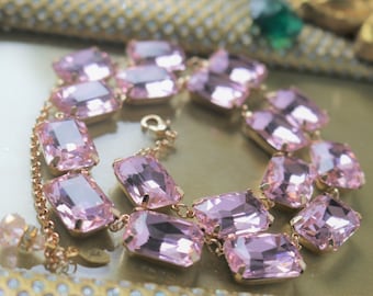 May include: A pink crystal necklace with a gold chain and a small charm. The necklace is made of rectangular-shaped crystals.