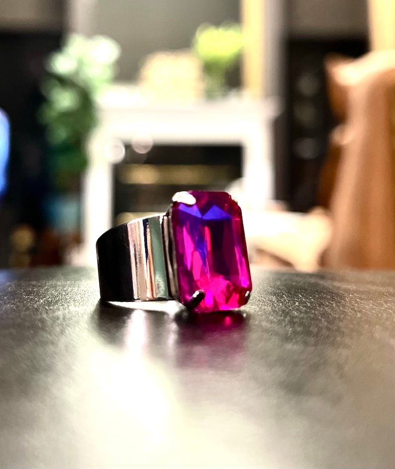 May include: A silver ring with a large, rectangular, fuchsia-colored gemstone.