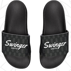 Peut inclure: Paire de sandales noires avec une semelle intérieure texturée. La bride affiche le mot "Swinger" en écriture blanche au-dessus de "LIFESTYLE" et un motif d'ananas gris. Les sandales sont de "BOLD SWING APPAREL".