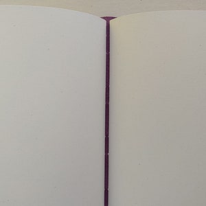 Puede incluir: Primer plano de un libro con una encuadernaci&oacute;n morada. Las p&aacute;ginas est&aacute;n en blanco y el libro est&aacute; cerrado.