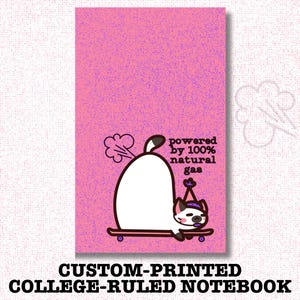 May include: Custom-printed college-ruled notebook with a pink background. The notebook features a cartoon cat on a skateboard, with the text "powered by 100% natural gas."