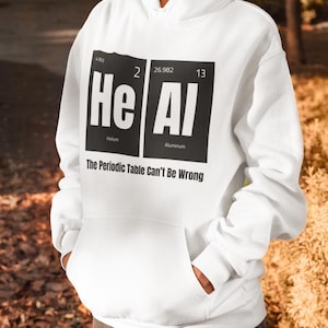May include: White hoodie featuring a black graphic of the periodic table elements Helium (He) and Aluminium (Al) with the text "The Periodic Table Can't Be Wrong".