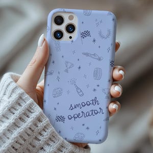 Puede incluir: Funda de teléfono azul claro con temática de carreras. La funda presenta un patrón repetido de banderas de carreras, coches de carreras, neumáticos y estrellas. Las palabras "smooth operator" están escritas en cursiva.