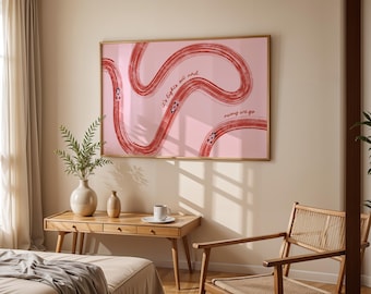 Op de afbeelding: Een ingelijste roze kunstprint met een rood abstract ontwerp en de tekst "it's lights out and away we go". Het kunstwerk hangt boven een houten bureau met een vaas en een kopje. Een rieten stoel staat in de buurt.