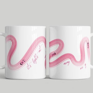 May include: White ceramic mug with a pink abstract design. The design features a winding pink line with small car illustrations and the text "It's lights out and away we go".