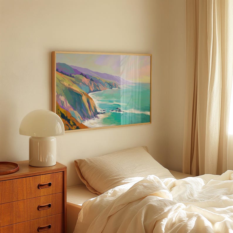 May include: A framed landscape painting depicts a coastal scene with cliffs, ocean, and sky. The artwork features a palette of blues, greens, purples, and yellows. The painting is displayed above a bed with cream-colored bedding.