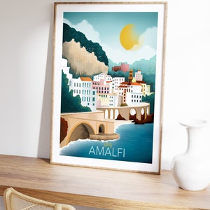 May include: A framed art print featuring a stylized illustration of Amalfi, Italy. The artwork depicts a coastal town with colorful buildings, a bridge, and the text "Italy Amalfi". The color palette includes blues, yellows, and whites.