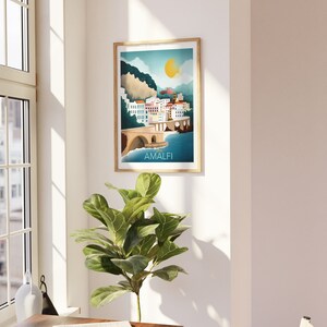 May include: A framed art print featuring a colorful illustration of Amalfi, Italy. The artwork depicts a coastal town with white buildings, a bridge, and a bright yellow sun. The word "AMALFI" is printed at the bottom of the image.