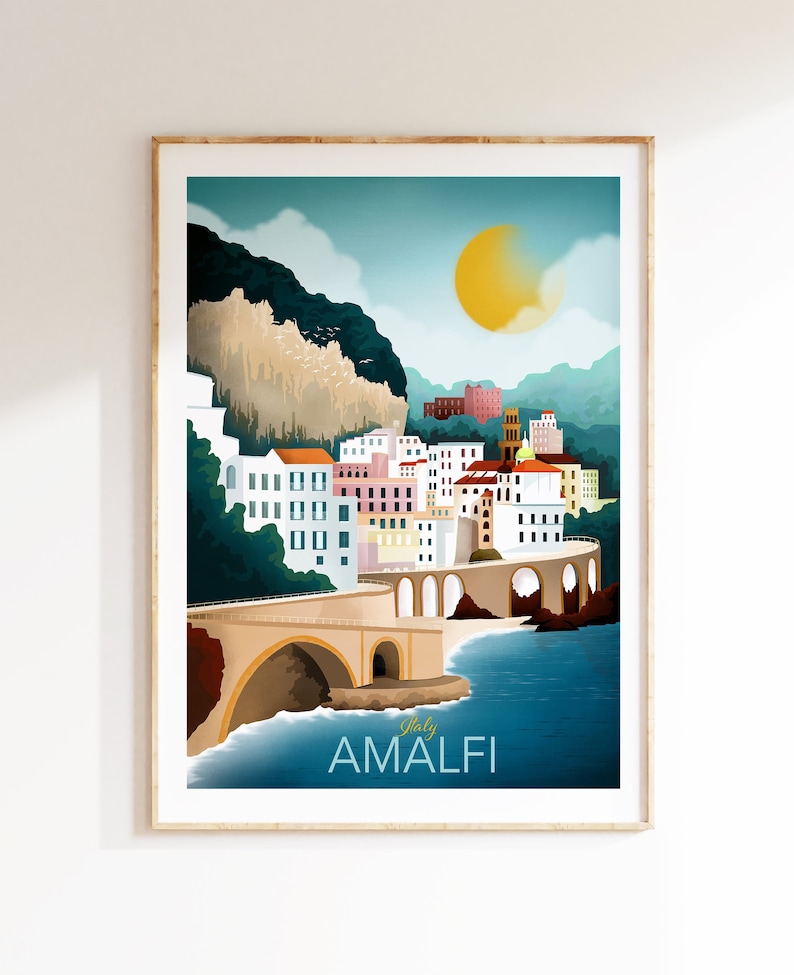 May include: A framed art print of Amalfi, Italy, featuring a coastal town with colorful buildings, a bridge, and a bright yellow sun. The text "Italy AMALFI" is at the bottom of the print. The artwork has a vintage travel poster style.
