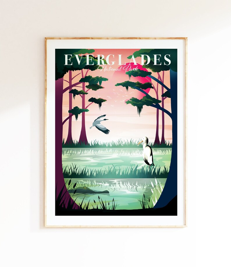 May include: A framed art print featuring a stylized Everglades National Park landscape. The artwork depicts a swamp scene with trees, birds, and an alligator, under a pink sun. The text "EVERGLADES National Park" is at the top.